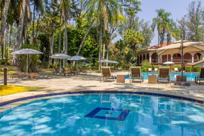 Una piscina al aire libre, sombrillas, sillones reclinables de piscina