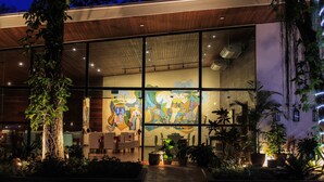 A modern building with large glass windows, indoor plants, and a mural on the wall.