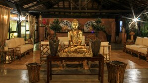 A room with a large golden Buddha statue, wooden furniture, and traditional decor.