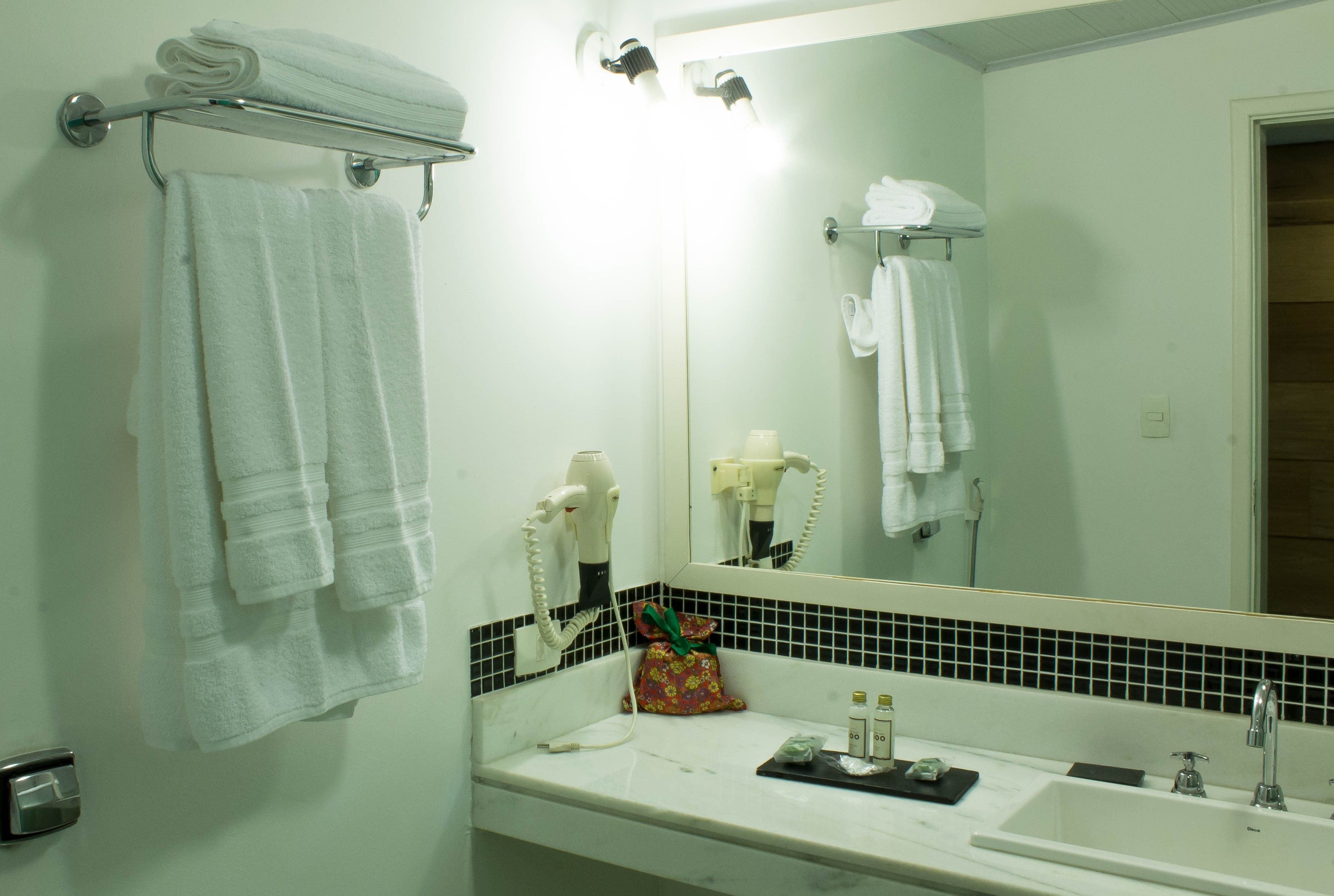 Un baño con lavabo, espejo, toallero y secador de pelo.