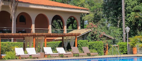 Una piscina al aire libre, sombrillas, sillones reclinables de piscina