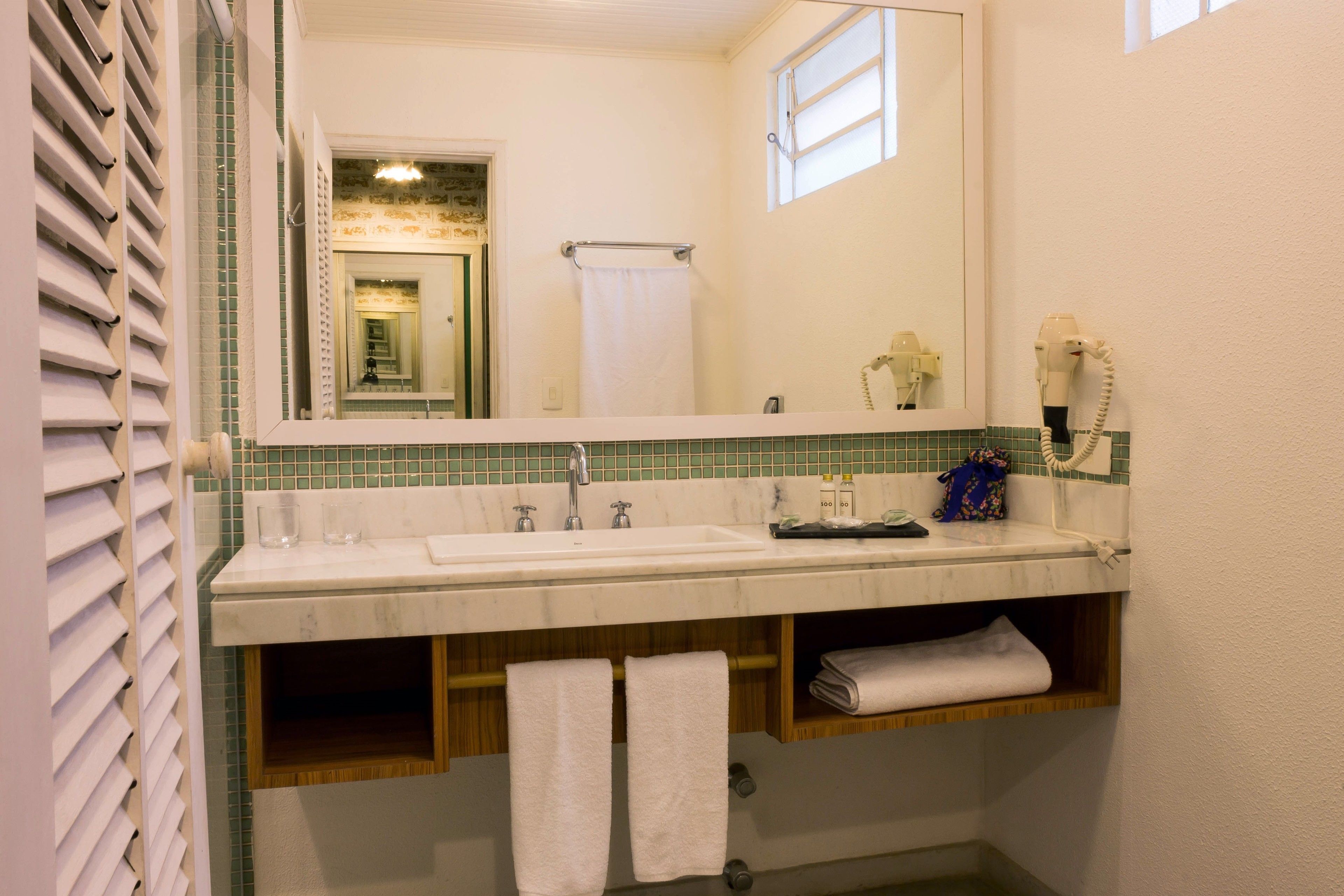 A bathroom with a white sink, a mirror, a towel rack, and a hairdryer.