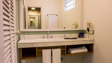 A bathroom with a white sink, a mirror, a towel rack, and a hairdryer.