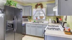 A kitchen with grey cabinets, a black refrigerator, a microwave, a sink, and a gas stove. - 5 Mi to Dtwn ATL! Family Home w/ Veranda & Yard (Atlanta)