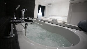 A modern bathroom with a large bathtub, a separate shower area, and a visible bed in the background. - Tropea Luxury & Charm (Tropea)
