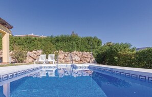 Una piscina amb gandules blanques, una paret de pedra i un cel blau clar.