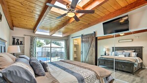 A bedroom with a large bed, a ceiling fan, a TV, and a sliding barn door. - Chic Central San Diego House w/ Private Pool! (San Diego)