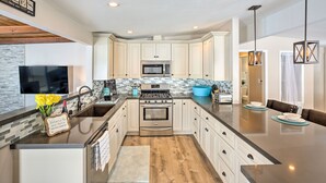 A modern kitchen with white cabinets, a stainless steel stove, and a blue bowl on the counter. - Chic Central San Diego House w/ Private Pool! (San Diego)