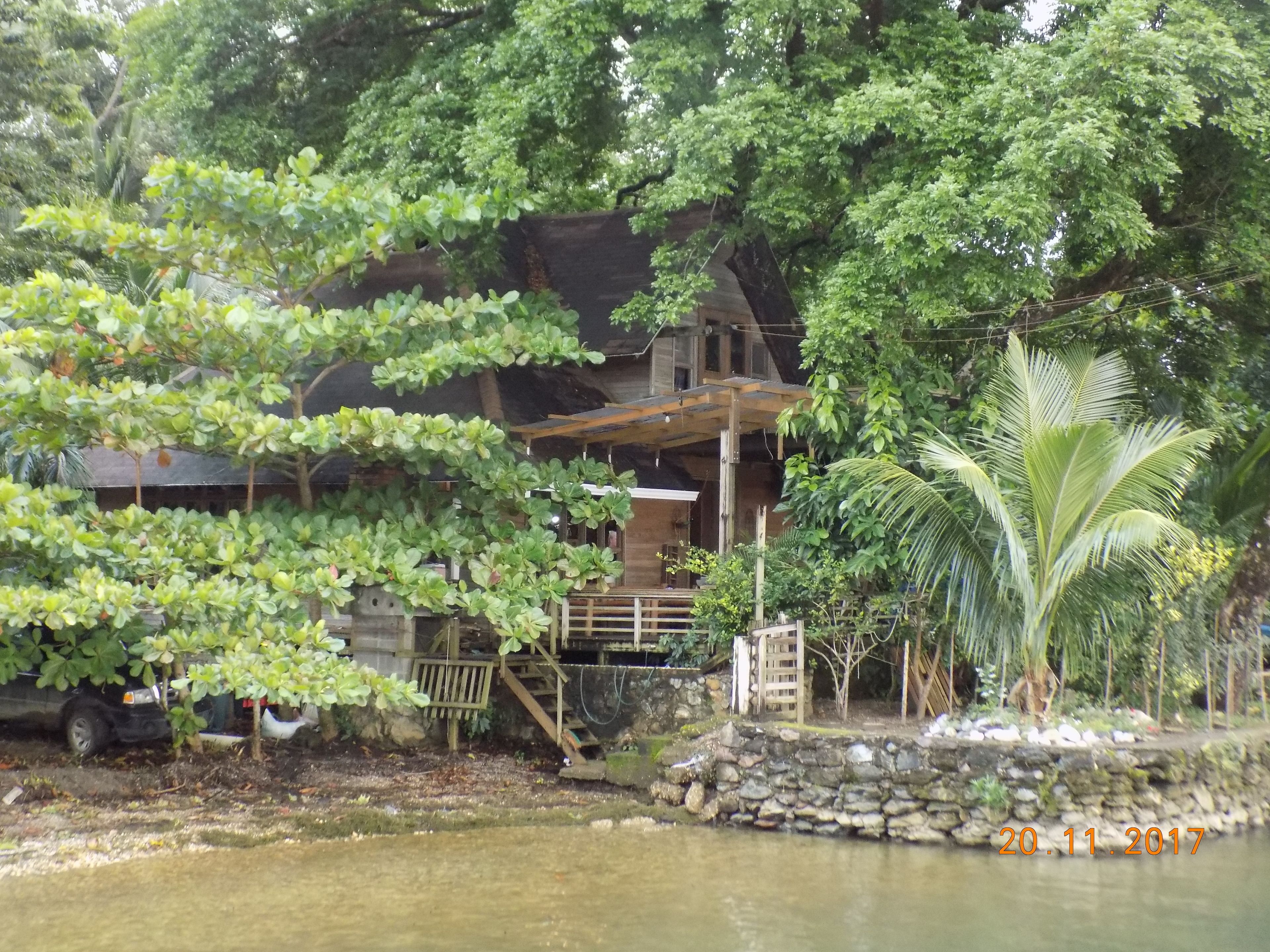 Ein rustikales Holzhaus mit einem Balkon, umgeben von üppigem Grün und einem Teich.
