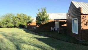 A backyard with a swimming pool, a wooden cabin, and a tall white building. - El Descanso (Colon)