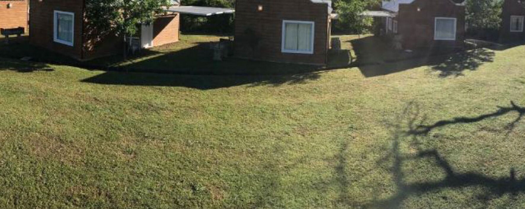 A grassy area with a small building, possibly a cabin or a house, with a window and a door.
