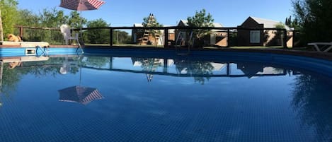 Una piscina al aire libre de temporada, sombrillas