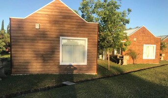 Um edifício moderno, térreo, com telhado inclinado e uma grande janela.