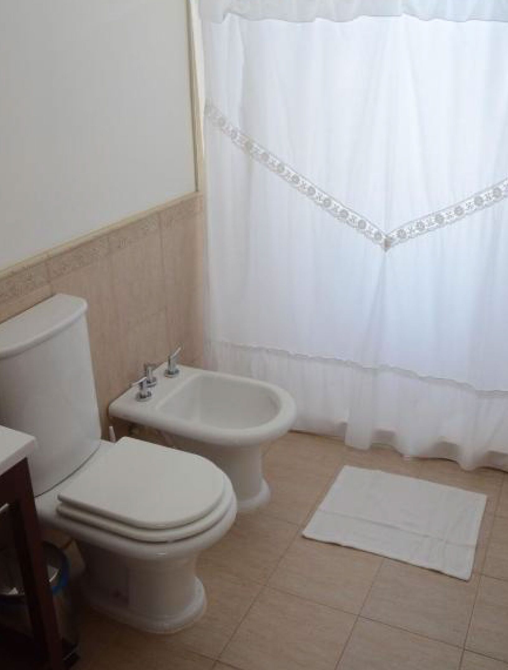 A bathroom with a toilet, bidet, and a white shower curtain.