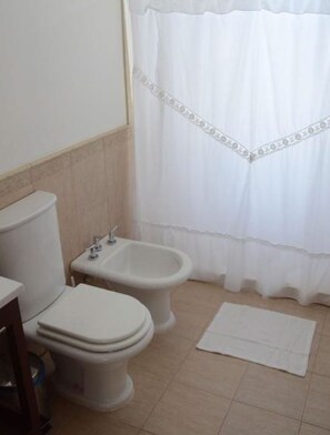 A bathroom with a toilet, bidet, and a white shower curtain.