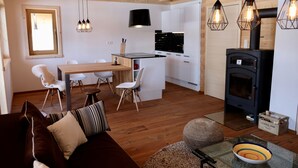 Une cuisine moderne avec des meubles blancs, une cuisinière noire et des luminaires suspendus.