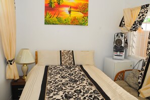A bedroom with a bed, a nightstand, a lamp, a radio, and a window with curtains. - Comfy bedrooms with swimming pool plus free wifi, spa hut, bbq, 24-hour security (Ohco Rios)
