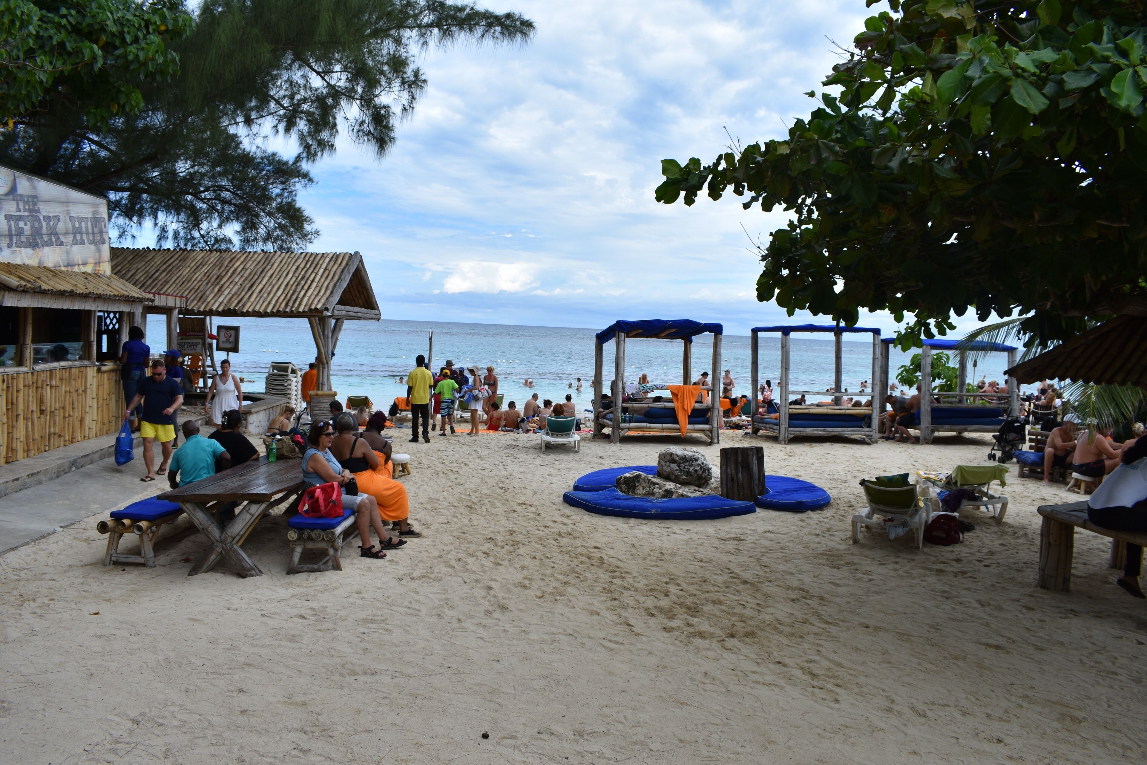 A beach with wooden benches and tables, a wooden structure, and a view of the sea.