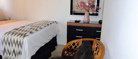 A bedroom with a bed, a dresser, a chair, and a mirror.
