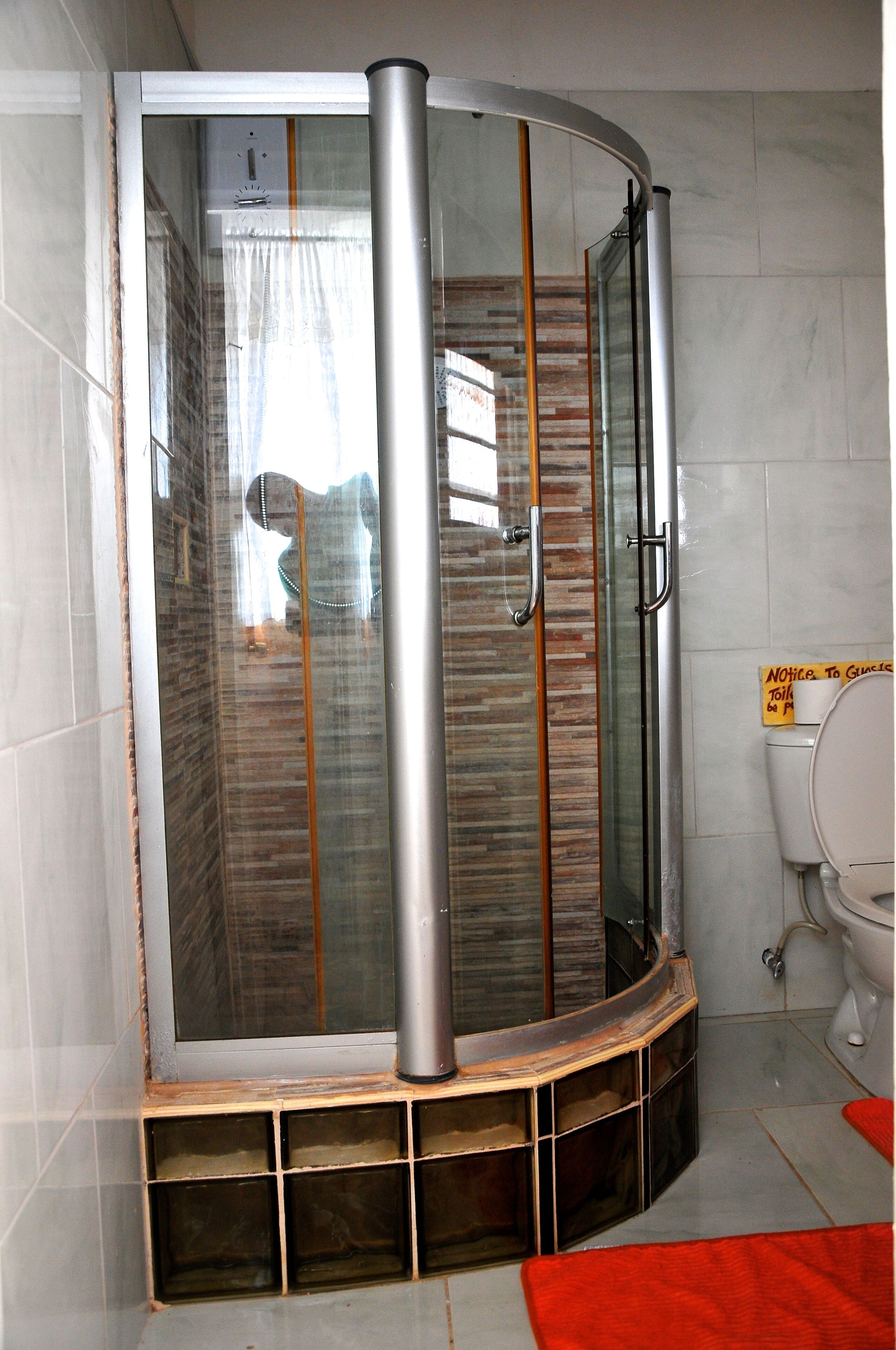 A shower enclosure with a glass door, a metal handle, and a tiled floor.