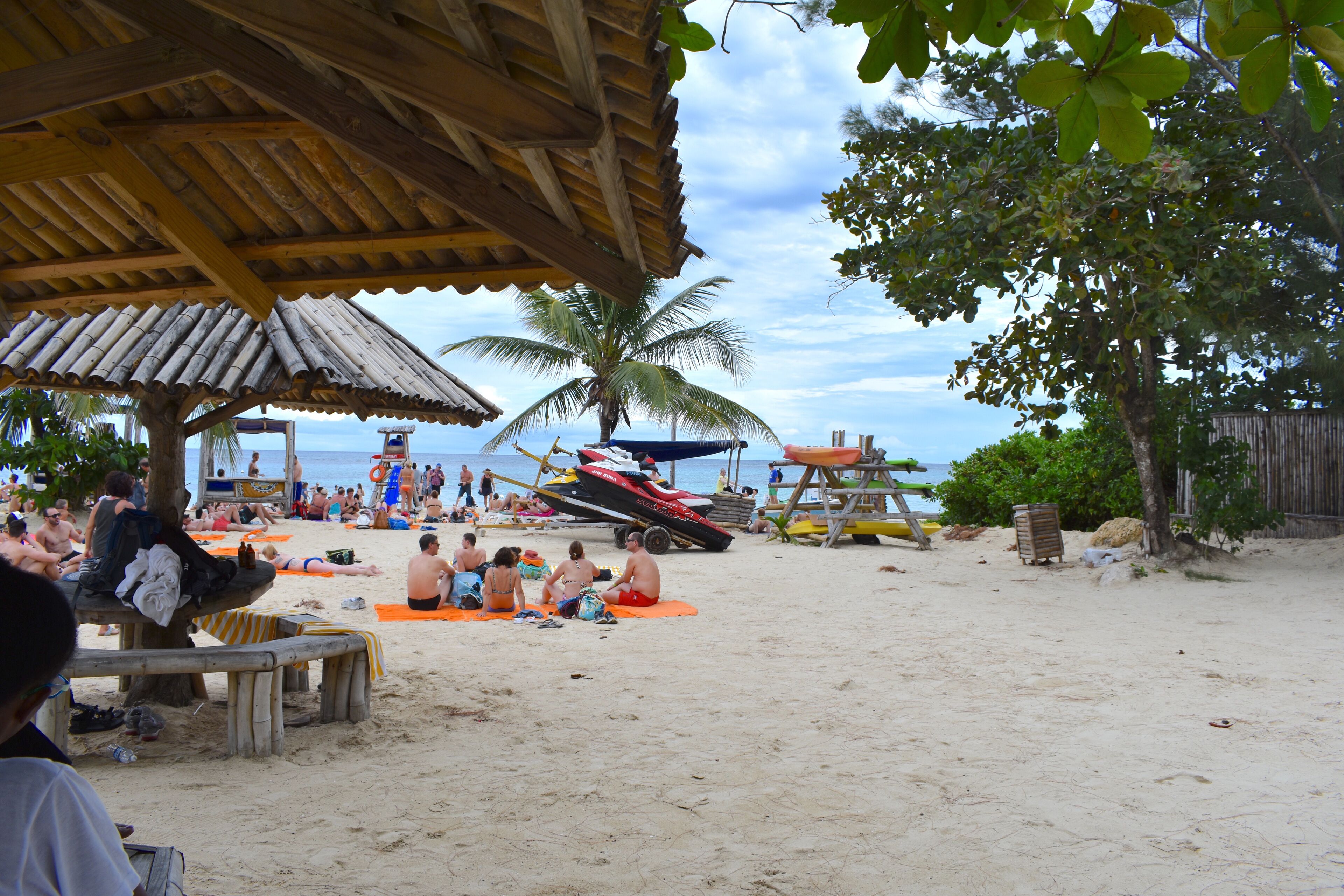 Una playa con gente tomando el sol y un barco al fondo.