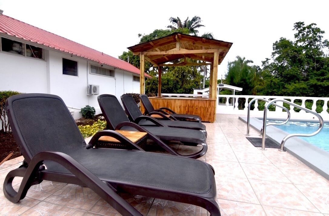 Un espace aménagé au bord de la piscine, avec des chaises longues et un gazebo en bois.