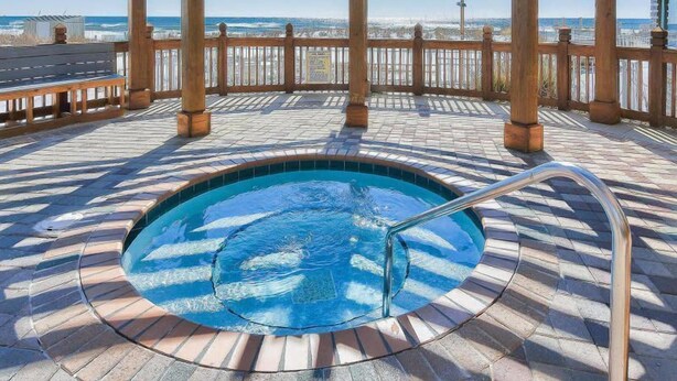 A wooden deck with a hot tub, wooden pergola, and a view of the ocean. - Perfect family retreat! Large deck for relaxing the sun! (Destin)