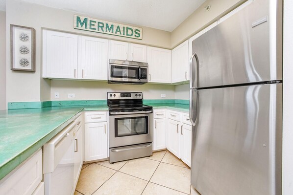 A kitchen with white cabinets, a stainless steel refrigerator, a microwave, and an oven. - Perfect family retreat! Large deck for relaxing the sun! (Destin)