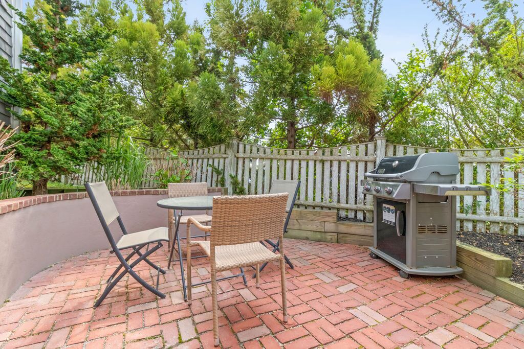 En udendørs terrasse med fletstole og grill.