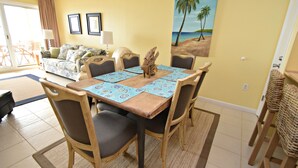 A dining area with a wooden table, six chairs, and a blue placemat. - Relax and Catch a couple fish! Drop all your worries it's vacation time. 🕮🏖️ (Gulf Shores)