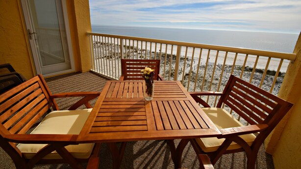 A wooden table and chairs on a balcony with a view of the beach and ocean. - Relax and Catch a couple fish! Drop all your worries it's vacation time. 🕮🏖️ (Gulf Shores)