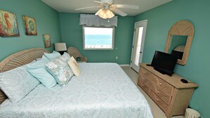 A bedroom with a bed, a dresser, a television, and a window with a view of the beach. - Relax and Catch a couple fish! Drop all your worries it's vacation time. 🕮🏖️ (Gulf Shores)