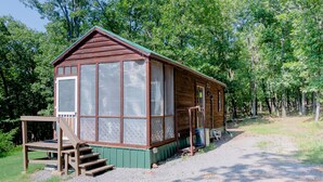 A wooden cabin with a porch, large windows, and a gravel path leading to it.