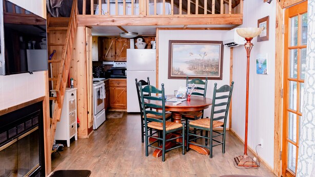 A cozy cabin with a dining area, kitchen, and a loft bedroom.