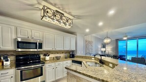 Una cocina moderna con armarios blancos, electrodomésticos de acero inoxidable y una isla grande con un lavamanos.