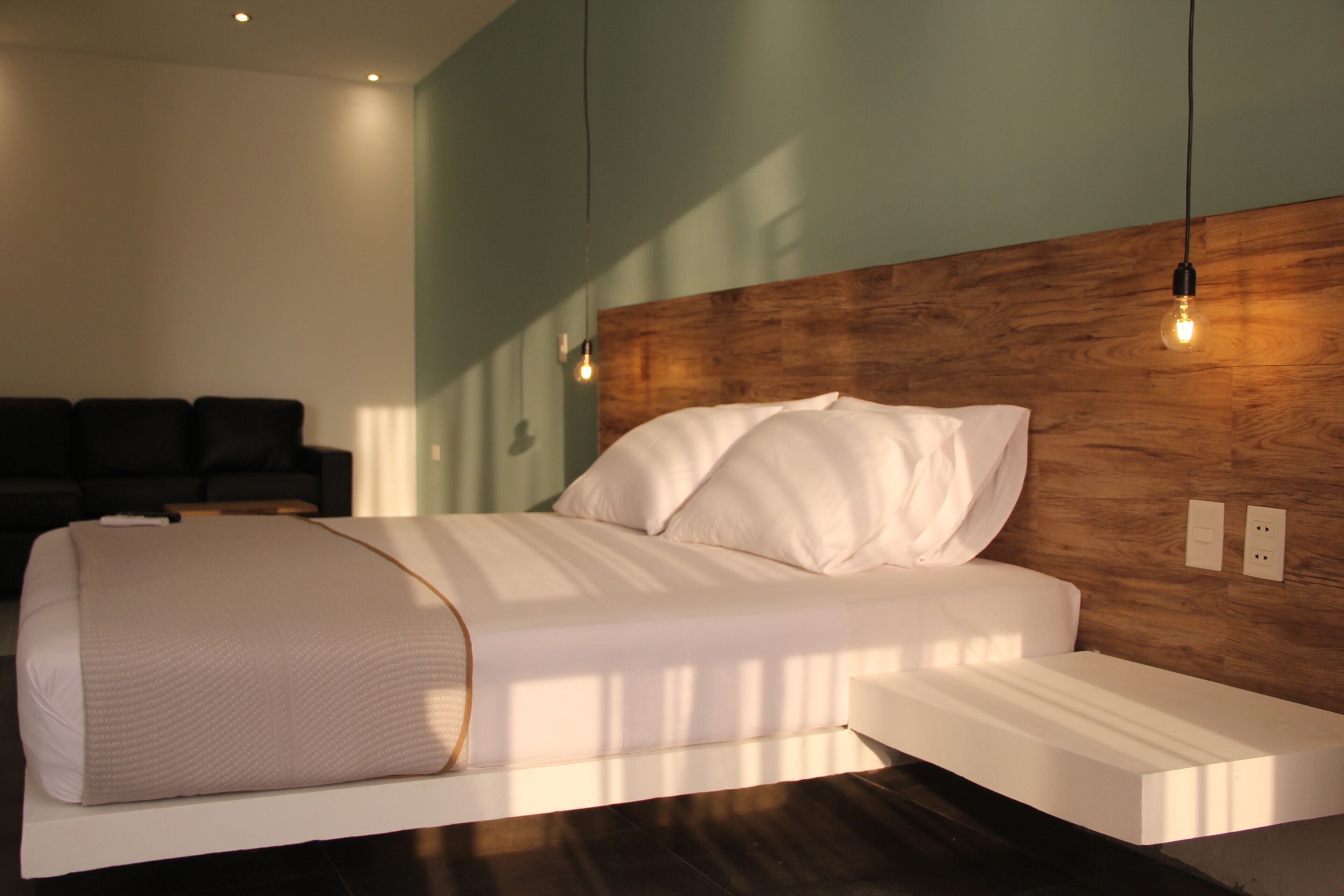 Een moderne slaapkamer met een houten hoofdbord, een groot bed met witte lakens en een nachtkastje.