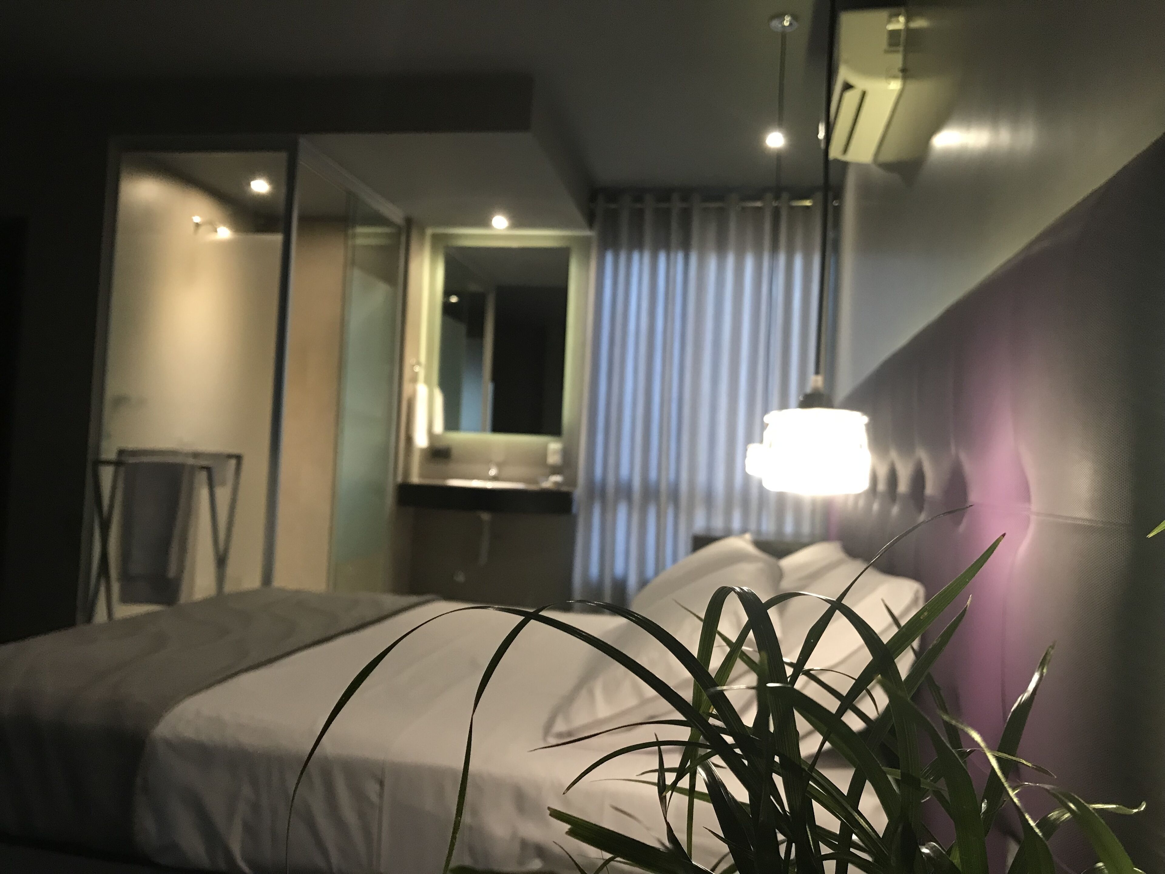 A modern hotel room with a bed, a bathroom, and a mirror.