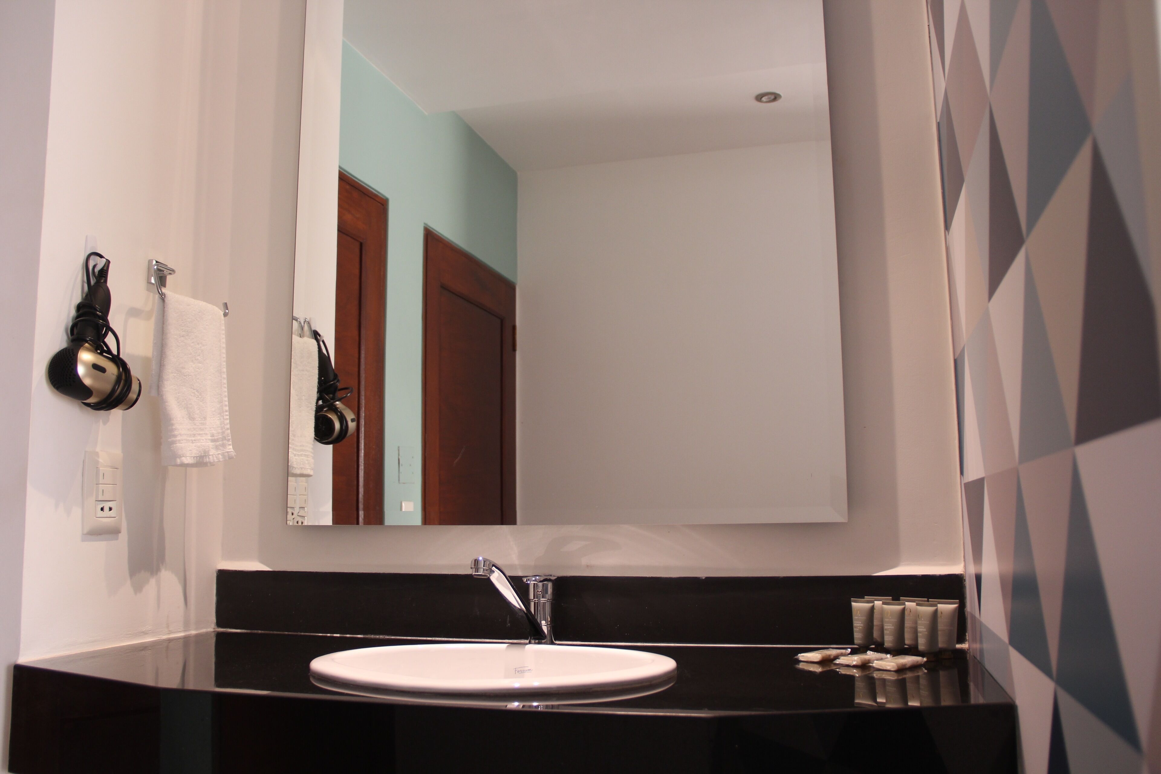 A bathroom with a black countertop, a white sink, and a mirror above it.