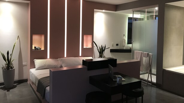 Een moderne slaapkamer met een bed, nachtkastje en een bureau met een laptop.