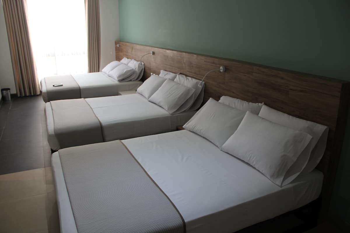 A hotel room with two single beds, a wooden headboard, and a large window with curtains.