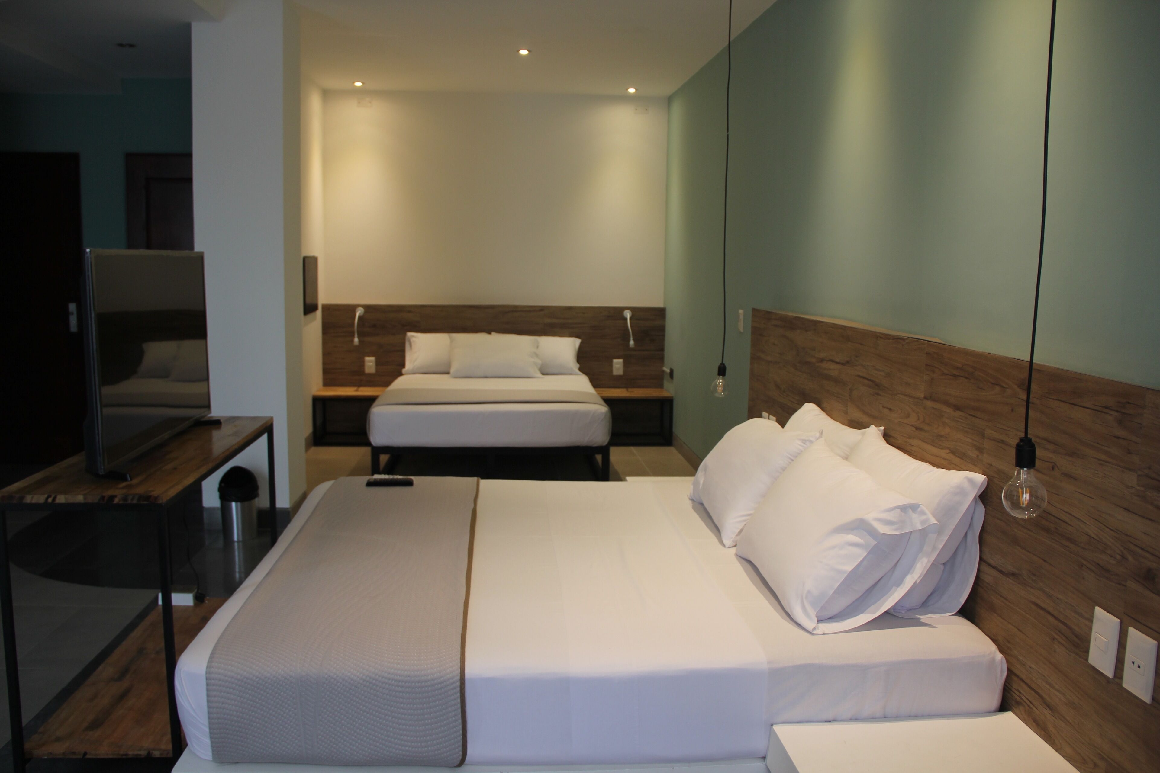 Une chambre d’hôtel moderne avec un grand lit, une télévision et une tête de lit en bois.