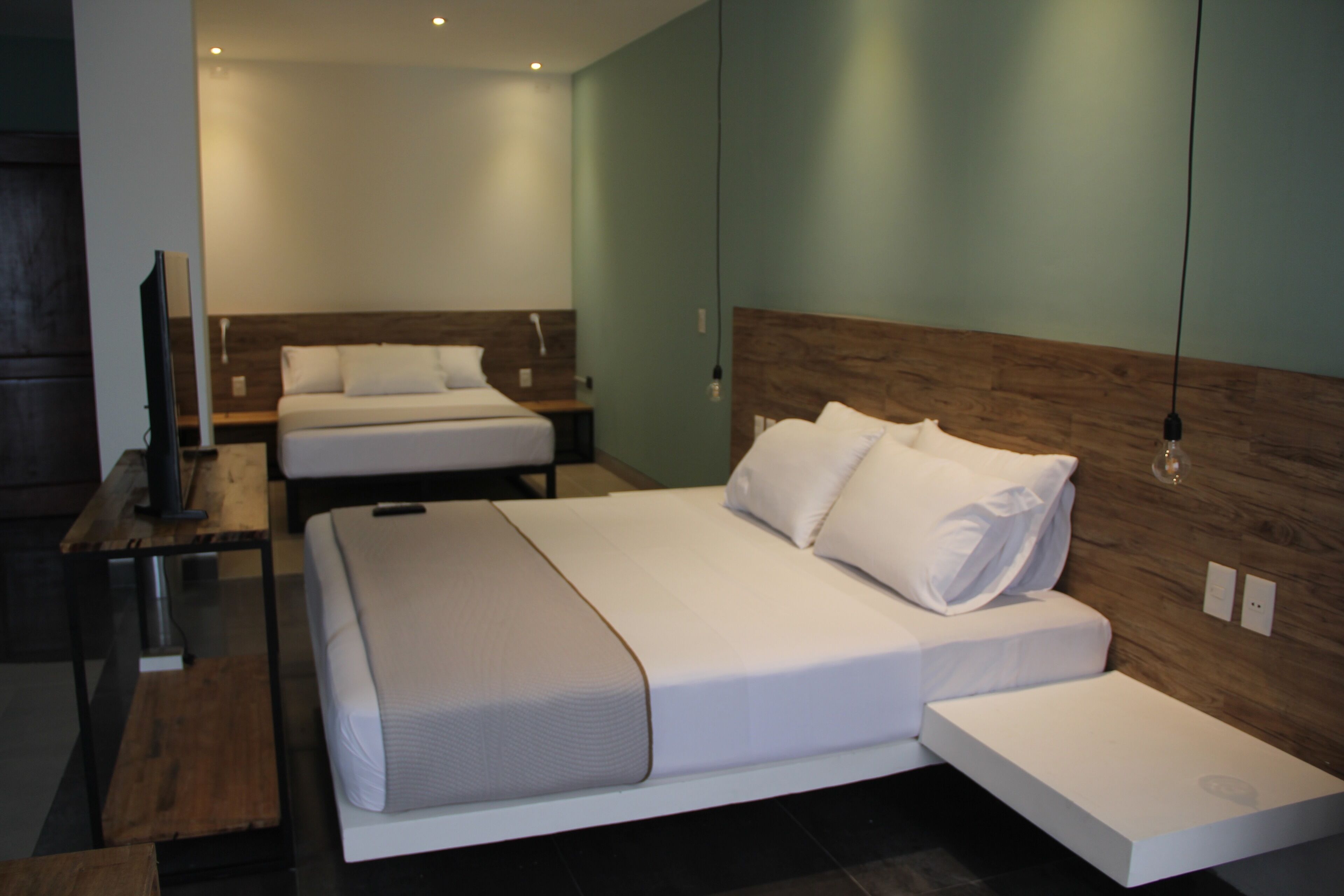A modern hotel room with a large bed, a smaller bed, a desk, and a TV.