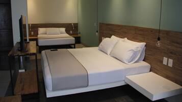 A modern hotel room with a large bed, a smaller bed, a desk, and a TV.