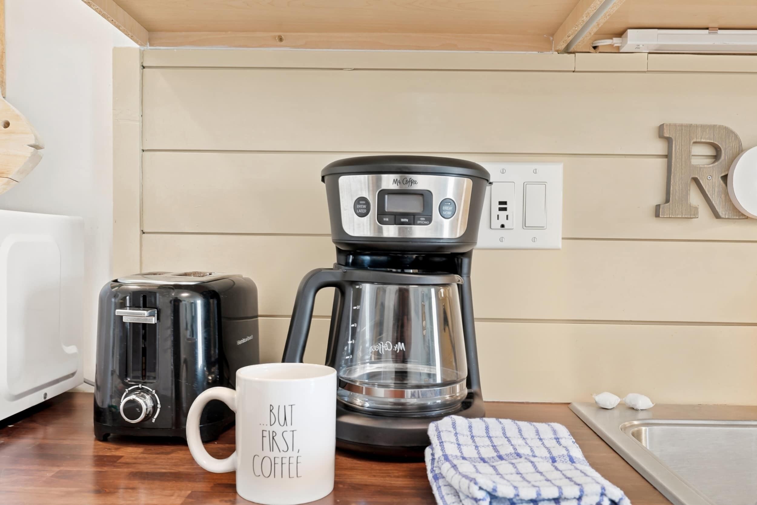 A kitchen with a coffee maker, a toaster, and a mug on the counter.