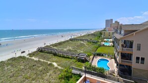 Un hotel sul lungomare con vista sulla spiaggia, piscina e passerella.