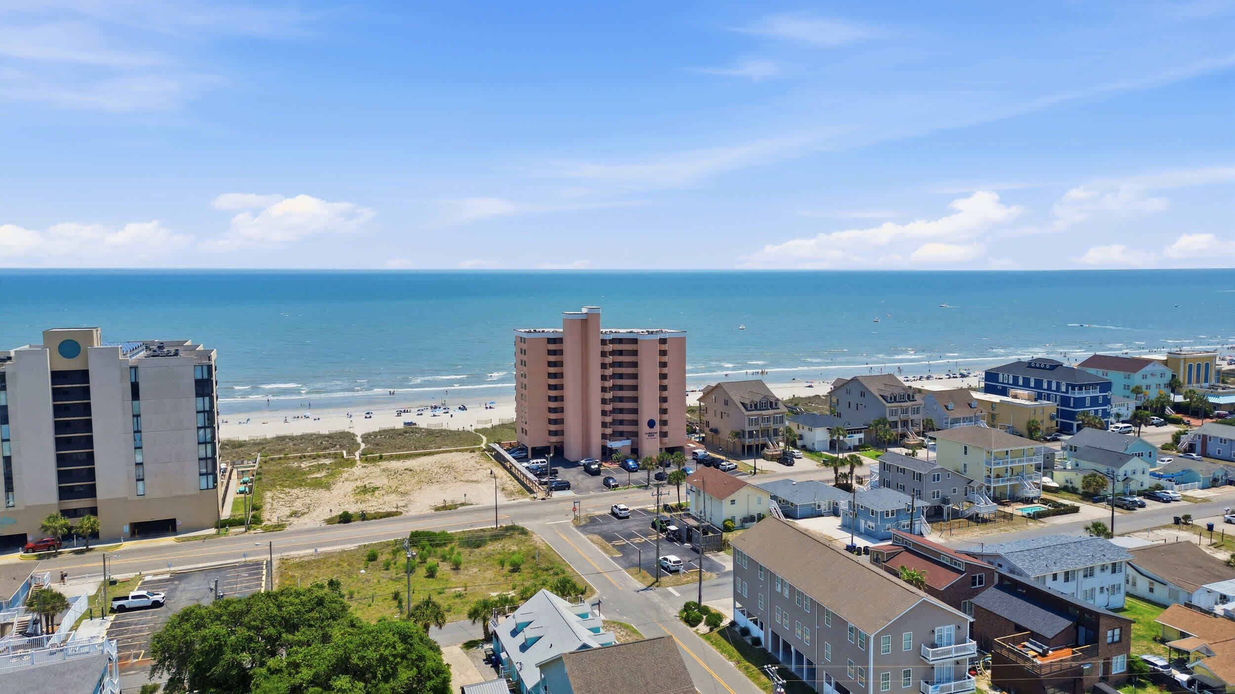 A coastal cityscape with a prominent hotel, beachfront, and residential buildings.