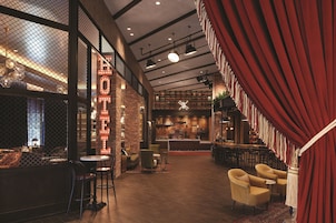 A cozy, well-lit lounge area with a bar, comfortable seating, and a visible staircase leading to an upper level.