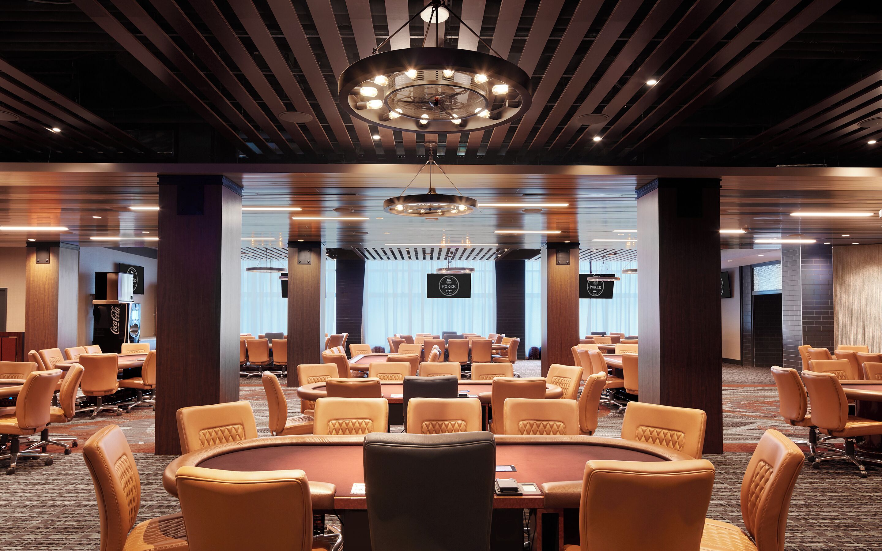 A conference room with a large oval table surrounded by leather chairs, a modern chandelier, and a large screen displaying 'POKER'.