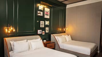 Habitación de hotel con dos camas, una mesita de noche e iluminación empotrada.
