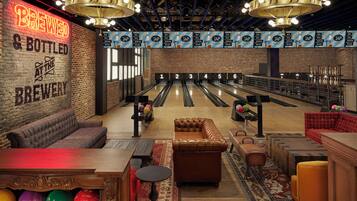 A bowling alley with a neon sign reading "BREWED & BOTTLED AT THE BREWERY" and multiple bowling lanes.